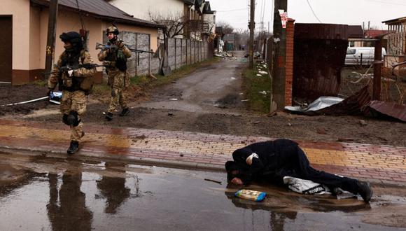 Los militares pasan junto al cuerpo de un hombre, que según los residentes fue asesinado por soldados rusos, acostado en la calle, en medio de la invasión de Rusia a Ucrania, en Bucha, Ucrania.