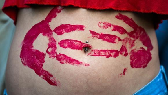 Una mujer joven, con el vientre manchado con marcas de manos de pintura roja. (Foto: Alberto PIZZOLI / AFP)