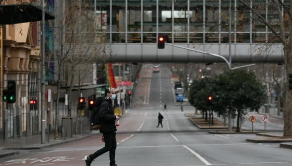 Un peatón cruza una calle en el centro de Melbourne el 6 de agosto de 2021, en medio de un sexto cierre de la ciudad en un esfuerzo por poner freno al brote de  la variante Delta del coronavirus. (Foto de Con Chronis / AFP).