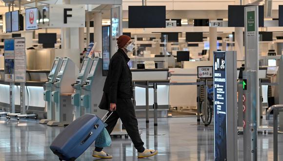Un hombre pasa frente a los mostradores de facturación en la zona de salidas de vuelos internacionales en el aeropuerto de Haneda de Tokio, Japón, el 1 de diciembre de 2021. (Kazuhiro NOGI / AFP).