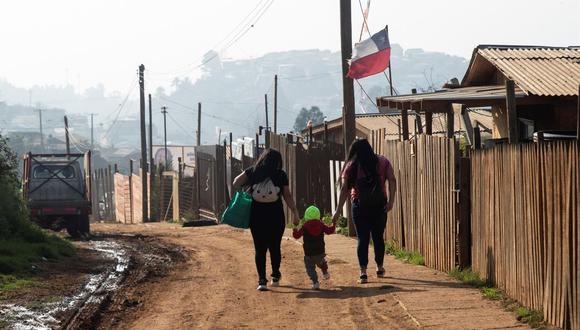 Dos mujeres caminan con un niño en una de las calles del Campamento Felipe Camiroaga el 30 de abril de 2021, en la ciudad de Viña del Mar, Chile. (EFE/Alberto Valdés).