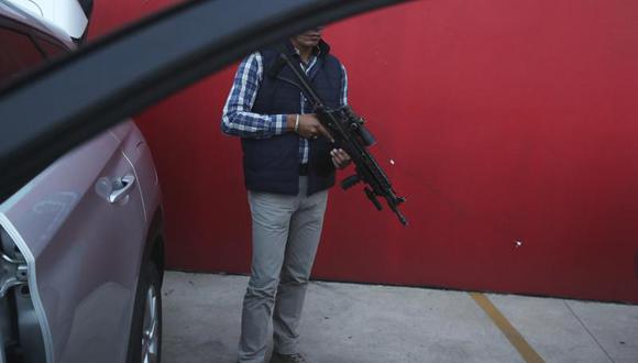 Un guardaespaldas asignado por el gobierno para el candidato a alcalde Guillermo Valencia permanece en guardia el sábado 22 de mayo de 2021 durante una de las escalas de campaña de ese candidato del PRI en Morelia, estado de Michoacán, México. (AP Foto / Marco Ugarte).