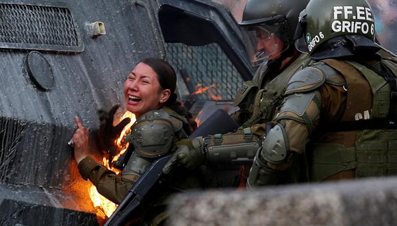 Una carabinera es alcanzada por una bomba molotov durante una protesta en Santiago de Chile. REUTERS/Jorge Silva).