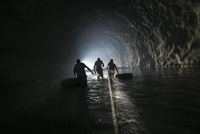 Los hombres, equipados con tubos internos, atraviesan un túnel de carretera abandonado con la ayuda de una línea de seguridad mientras trabajan para reparar un sistema de agua creado por ellos mismos en el barrio Esperanza de Caracas, Venezuela. (AP Photo/Matias Delacroix).