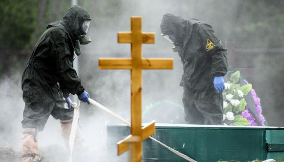 Trabajadores con equipo de protección entierran a una víctima del coronavirus en un cementerio en las afueras de Moscú, Rusia, el 15 de mayo de 2020. (Kirill KUDRYAVTSEV / AFP).