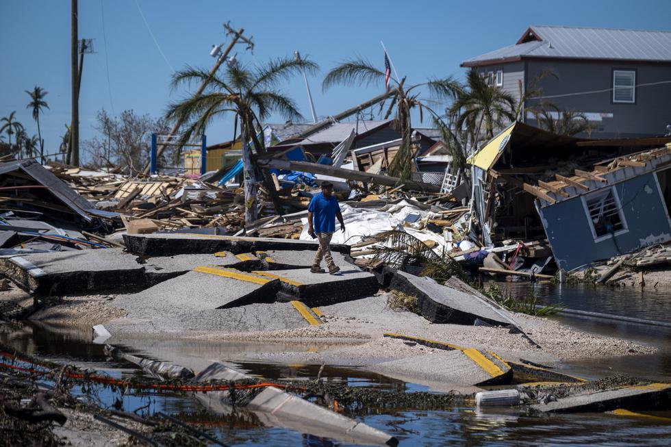 Un hombre camina sobre el asfalto destruido en Pine Island Road después del paso del huracán Ian en Matlacha, Florida, el 1 de octubre de 2022. (Foto de Ricardo ARDUENGO/AFP).