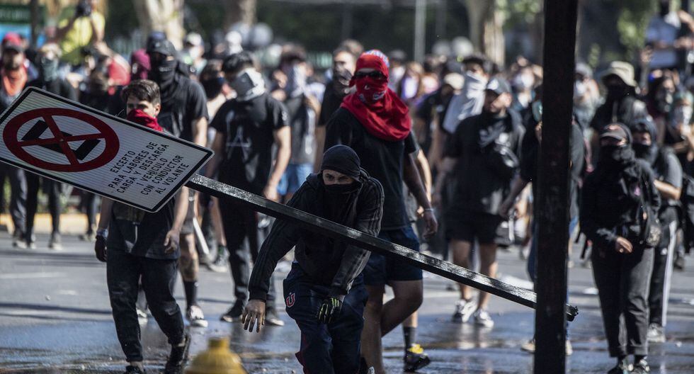 Manifestantes arrancan una señal de tránsito en Santiago. (Photo by Pedro UGARTE / AFP).