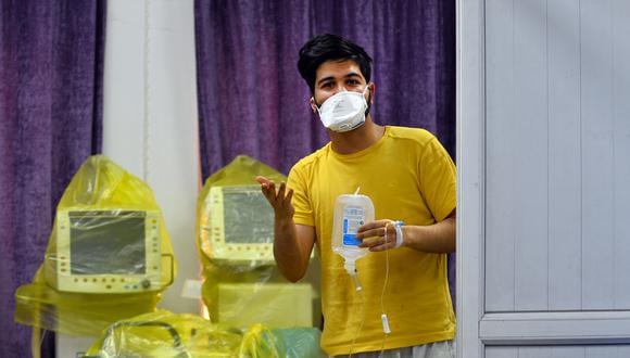 Un estudiante iraní, según los informes, el primer caso de coronavirus COVID-19 documentado en Irak, observa mientras está parado sosteniendo una bolsa de inyección intravenosa conectada a su muñeca, en una zona de cuarentena. (Foto: AFP)