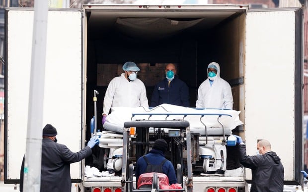 Los profesionales médicos y los empleados del hospital transfieren un cuerpo en una camilla del hospital a un almacenamiento temporal en una morgue móvil, que se utiliza debido a la falta de espacio en el hospital, fuera del Centro del Hospital de Brooklyn en Brooklyn, Nueva York (Foto: EFE / EPA / JUSTIN LANE)