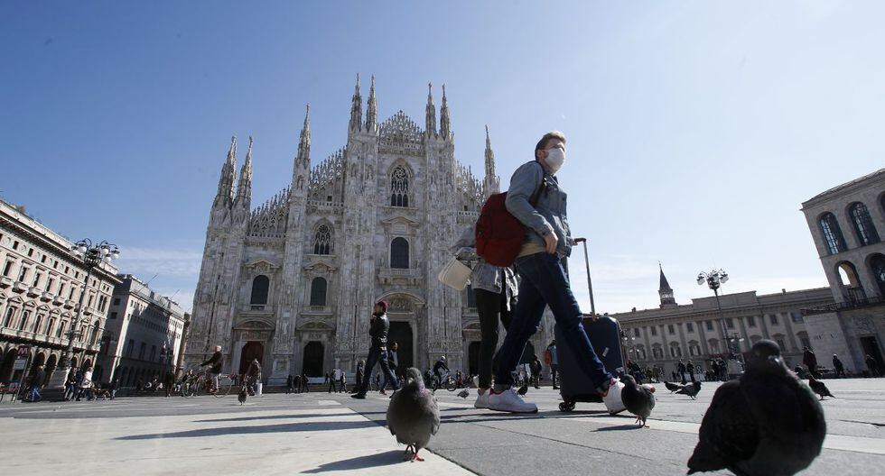 Esta foto de marzo muestra a un hombre con mascarilla caminando con su maleta frente a la catedral del Duomo, en el centro de Milán, Italia. (Foto: AP)