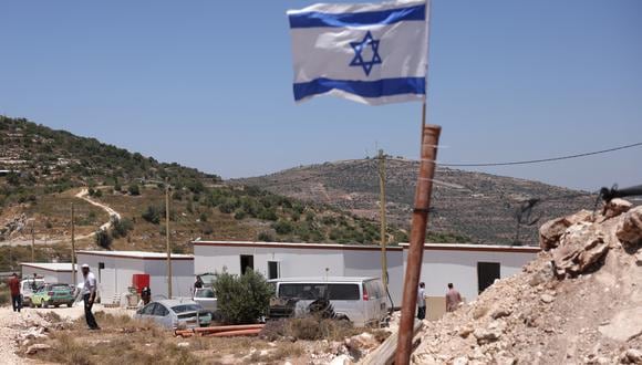 Una bandera nacional israelí ondea cerca de estructuras prefabricadas durante la construcción de un nuevo puesto de avanzada, cerca del asentamiento de Ma'ale Levona en la Cisjordania ocupada. (Foto de Menahem KAHANA / AFP)