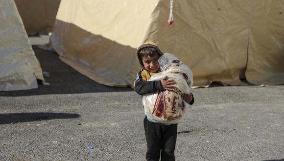 Un niño sirio lleva pan en un refugio improvisado para personas que quedaron sin hogar, cerca de la ciudad de Jindayris, controlada por los rebeldes, el 9 de febrero de 2023, dos días después de que un terremoto mortal azotara Turquía y Siria. (Foto de Aaref WATAD / AFP)