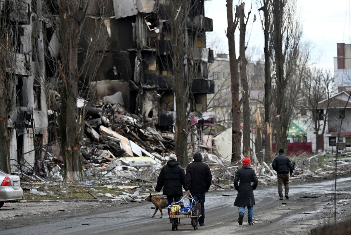 People walk past destroyed buildings in the city of Borodianka, northwest of kyiv, on April 4, 2022. (Sergei SUPINSKY / AFP)