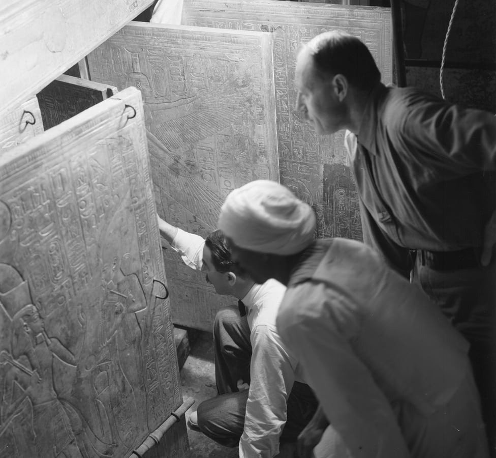 Howard Carter, his assistant Arthur Callender, and an unidentified Egyptian open the doors to a golden shrine inside Tutankhamun's tomb.  (HARRY BURTON/GRIFFITH INSTITUTE, UNIV. OF OXFORD).