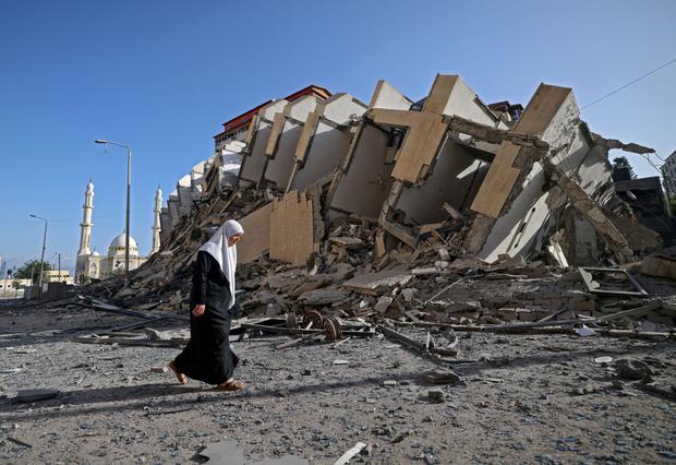 A Palestinian woman walks past a destroyed building in Gaza City. (Photo by MOHAMMED ABED / AFP).