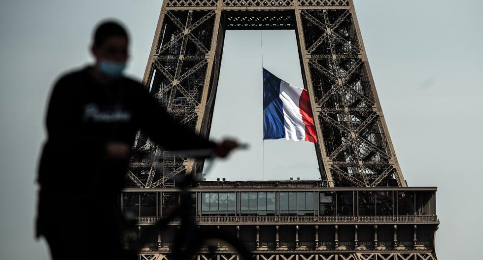 Un hombre con una máscara facial empuja su bicicleta en Trocadero Plaza mientras una bandera nacional francesa ondea en la Torre Eiffel en el fondo el pasado 11 de mayo de 2020, en el primer día de la flexibilización de las medidas de bloqueo en Francia para frenar la propagación del COVID-19. (Foto por PHILIPPE LOPEZ / AFP)