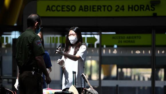 Una pasajera con una máscara facial muestra sus documentos en su teléfono a un oficial de seguridad en el aeropuerto de Barajas en Madrid, España, el 20 de junio de 2020. (PIERRE-PHILIPPE MARCOU / AFP).