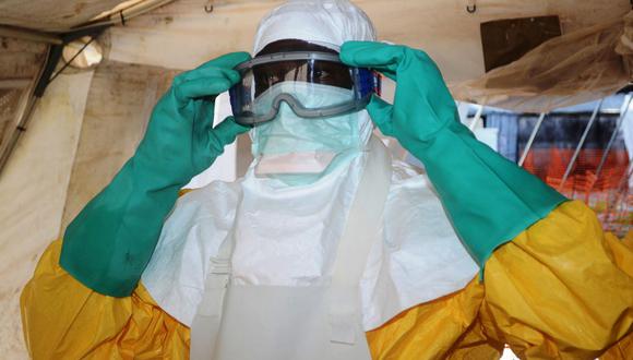 Esta foto de archivo tomada el 15 de agosto de 2014 muestra a un trabajador médico de MSF revisando su ropa protectora en un espejo en Kailahun, epicentro del peor brote de ébola del mundo. (Foto de CARL DE SOUZA / AFP).