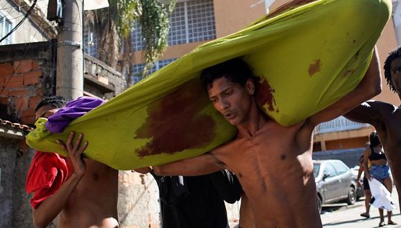 Residentes de la favela Complexo do Alemao cargan el cadáver de un hombre que falleció durante una redada policial en Río de Janeiro, Brasil, el 21 de julio de 2022. (Mauro Pimentel / AFP)