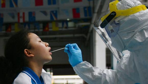 Un miembro del personal médico tomando muestras de hisopos de un estudiante para realizar pruebas de ácido nucleico para el coronavirus COVID-19. (Foto: STR / AFP / China OUT).