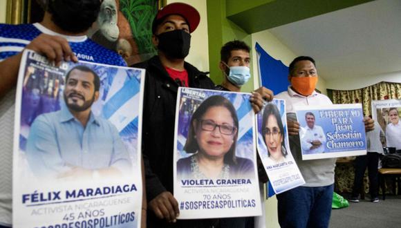 Nicaragüenses en el exilio sostienen carteles con las imágenes y nombres de presos políticos bajo el régimen de Daniel Ortega.