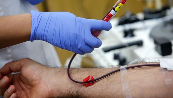 Un trabajador de salud extrae muestras de sangre de un voluntario recuperado de COVID-19. (Foto: GIL COHEN-MAGEN / AFP)