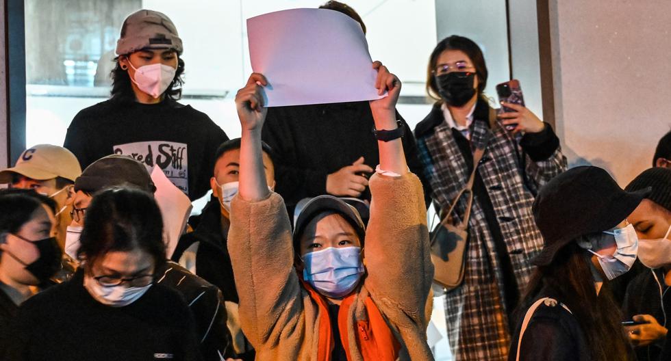 Las personas muestran papeles en blanco como una forma de protesta en una calle de Shanghái, China, el 27 de noviembre de 2022. (Foto por Héctor RETAMAL / AFP).