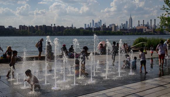 Los niños juegan en una fuente de agua frente a la ciudad de Manhattan en Nueva York, el 30 de junio de 2021 (Foto de Ed JONES / AFP).