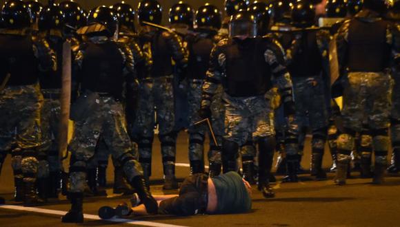 Un hombre yace en el suelo frente a la policía antidisturbios durante una protesta tras el cierre de las urnas en las elecciones presidenciales de Bielorrusia, en Minsk.  (Archivo/AFP/Sergei GAPON)