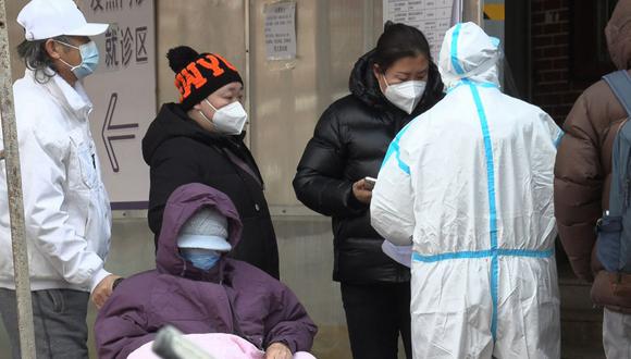 Un trabajador de la salud mientras la gente hace cola afuera de una clínica de fiebre en medio de la pandemia de covid-19 en Beijing el 14 de diciembre de 2022. (Foto de Yuxuan ZHANG / varias fuentes / AFP)