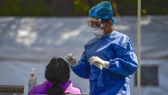 Un trabajador de la salud le hace la prueba a una persona para la enfermedad del coronavirus COVID-19, en la explanada del Hospital General Carlos MacGregor del IMSS en la Ciudad de México. (Foto: Pedro PARDO / AFP)