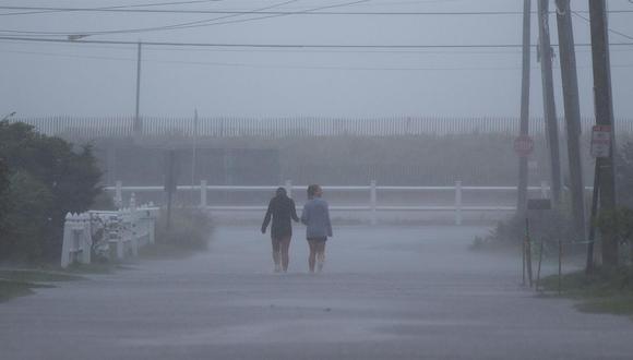 Dos peatones caminan por las calles inundadas a la llegada de la tormenta tropical Henri a la playa de Misquamicut en Westerly, Rhode Island. (EFE / EPA / CJ GUNTHER / referencial).