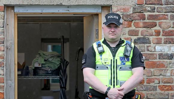 Un oficial de policía vigila la entrada trasera del café The Clean Plate en Gloucester, en el oeste de Inglaterra, donde se realizan excavaciones para buscar el cuerpo de la adolescente desaparecida Mary Bastholm. (Foto de Geoff Caddick / AFP).
