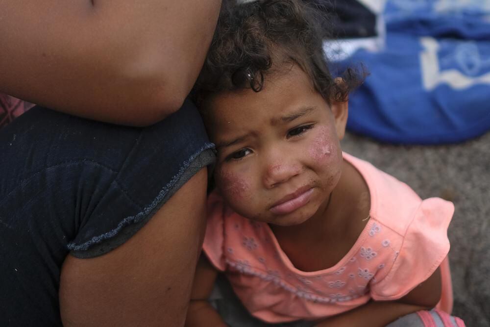 The daughter of Venezuelan migrant Magdelis Alejos rests her head on her mother after police told the family to dismantle the camp they had set up by the sea in El Morro, a neighborhood in Iquique, Chile.  (AP / Matias Delacroix)