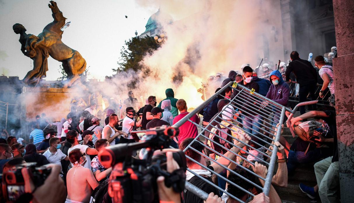 Las personas chocan con la policía frente al edificio de la Asamblea Nacional de Serbia en Belgrado durante una manifestación contra el toque de queda del fin de semana por coronavirus. (AFP / ANDREJ ISAKOVIC).