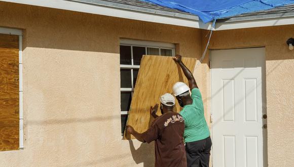 Los residentes cubren una ventana con madera contrachapada en preparación para la llegada del huracán Isaias, en el vecindario Heritage de Freeport, Gran Bahama, Bahamas, el viernes 31 de julio de 2020. (Foto AP / Tim Aylen).