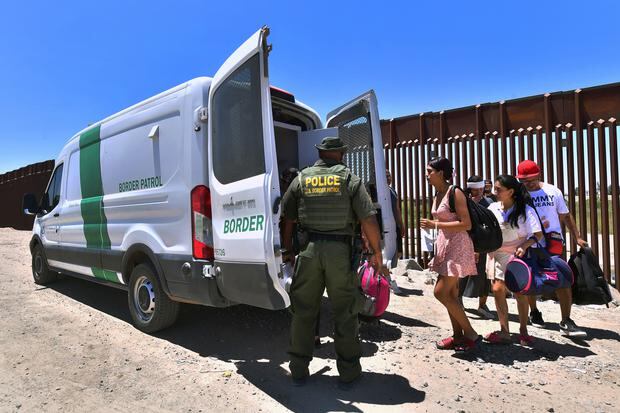 Un oficial de Aduanas y Protección Fronteriza de Estados Unidos (CPB) observa cómo los migrantes abordan una camioneta de la Patrulla Fronteriza para ser llevados para su procesamiento. (Foto de Frederic J. BROWN / AFP).