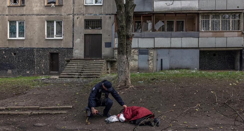 Un policía comprueba el pulso de un civil que ha sido asesinado en una zona residencial que fue atacada por un bombardeo de la artillería rusa este martes en Kharkiv, noreste de Ucrania. (EFE/ Roman Pilipey).