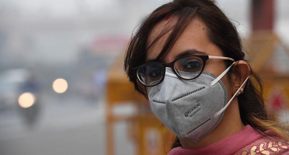 Una mujer con una máscara protectora espera el autobús público en condiciones altas de smog en Nueva Delhi. (AFP)