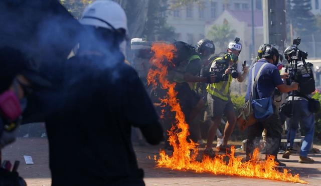 Un trabajador reacciona junto a un incendio de un cóctel Mototov lanzado por manifestantes durante enfrentamientos con la policía frente a la Universidad Politécnica de Hong Kong . (Foto: EFE)