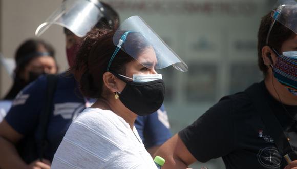 Personas con mascarillas y protectores faciales en las calles de Lima. (Foto: Eduardo Cavero/ GEC)
