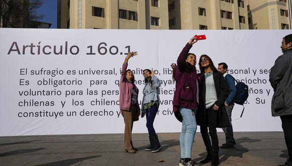 La gente se toma selfies frente a la pancarta que muestra el Artículo 160.1 que es parte de la nueva Constitución propuesta en Plaza Italia en Santiago, Chile.