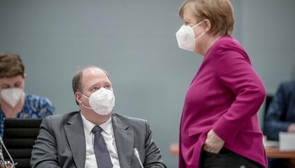 La canciller alemana, Angela Merkel, usa una mascarilla cuando pasa junto al jefe de gabinete alemán Helge Braun para presidir la reunión sobre la pandemia de coronavirus. (Foto de Michael Kappeler / POOL / AFP).