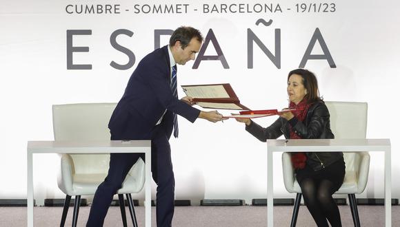 Los ministros de Defensa española, Margarita Robles (d), y galo, Sébastien Lecornu (i), intercambian documentos durante la ceremonia de firma de acuerdos celebrada en la Cumbre Hispanofrancesa, este jueves, en Barcelona. (Foto: EFE/Alberto Estévez)