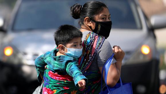 Una madre con su hijo lleva víveres de un evento de distribución de alimentos en Los Ángeles, Estados Unidos, país azotado por la pandemia de coronavirus. (Foto: REUTERS / Patrick T. Caer).
