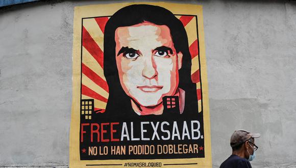La gente camina frente a un cartel con la imagen del empresario colombiano Álex Saab en Caracas, Venezuela. El supuesto mayor testaferro de Maduro está preso en Estados Unidos. (Yuri CORTEZ / AFP).