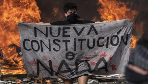Un manifestante sostiene un trozo de tela que dice "Nueva Constitución o nada" durante una manifestación en Plaza Italia en Santiago. (Foto: Archivo/AFP / Pedro UGARTE).