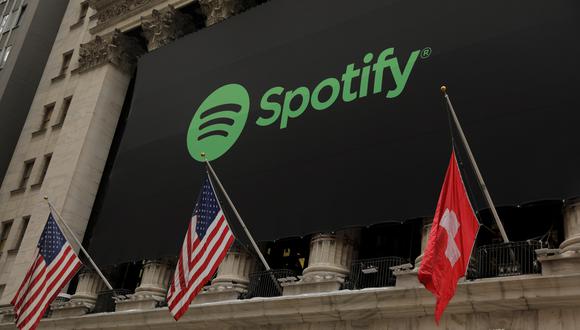 El logo de Spotify se luce en la fachada de la Bolsa de Valores de Nueva York en EE. UU. junto con una bandera suiza.