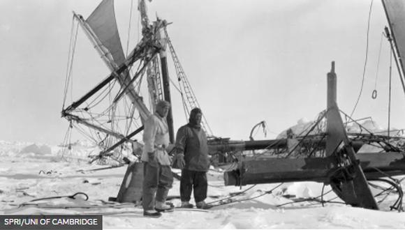 Shackleton (R) observa los restos rotos de su barco justo antes de que se hundiera en las profundidades.