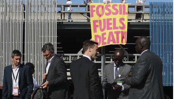 Activistas medioambientales de Extinction Rebellion sostienen una pancarta que dice "Combustibles fósiles-Muerte" mientras protestan en la Semana.